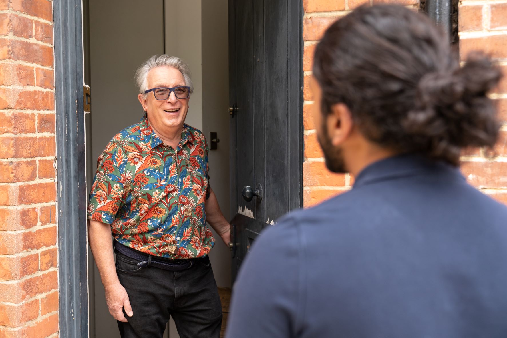 Male homeowner opening the front door to an engineer arriving at the property