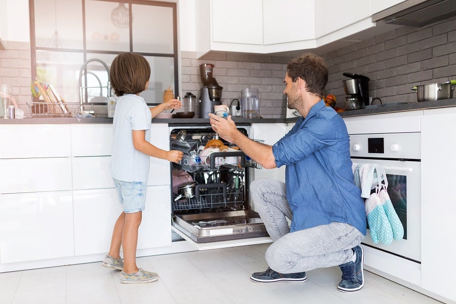 Caucasian father and his young son loading the dishwasher together